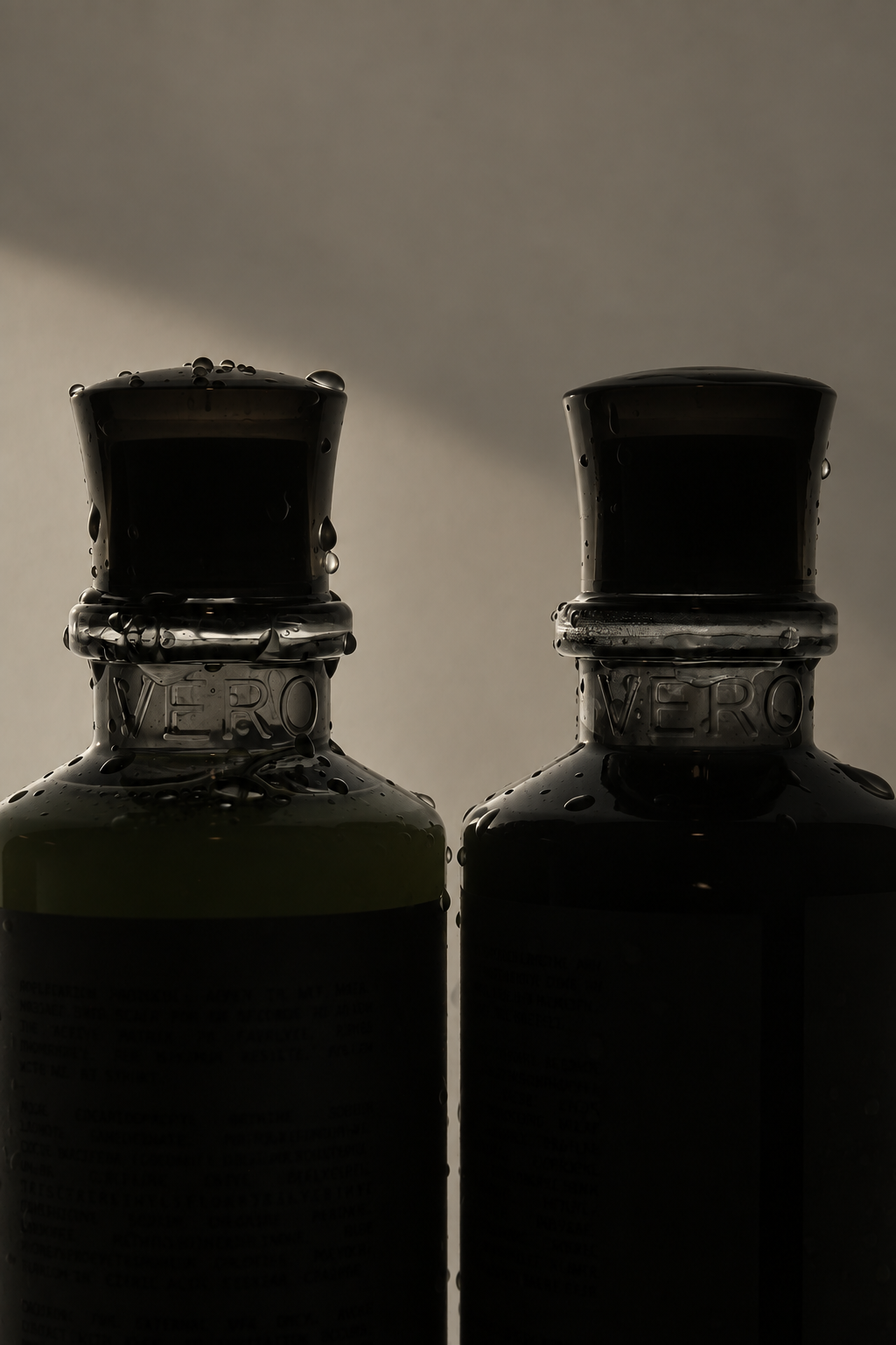 Two VERO bottles with water droplets in soft, low light